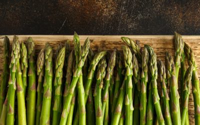 Freshly picked organic asparagus tips on wooden board.